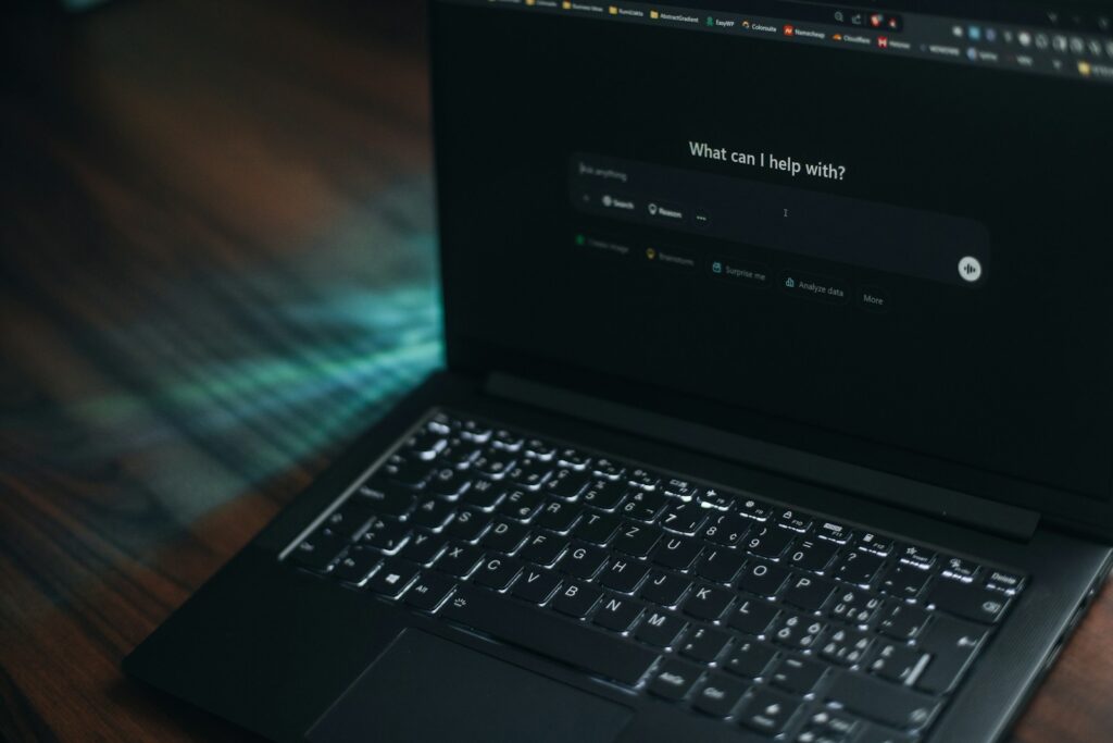 A laptop displays a search bar asking how it can help.
